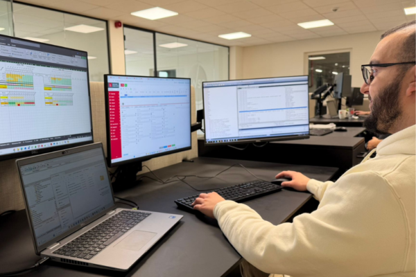 Amine, a data analyst at Weerts Supply Chain, sits in front of several computer screens displaying spreadsheets and dashboards.